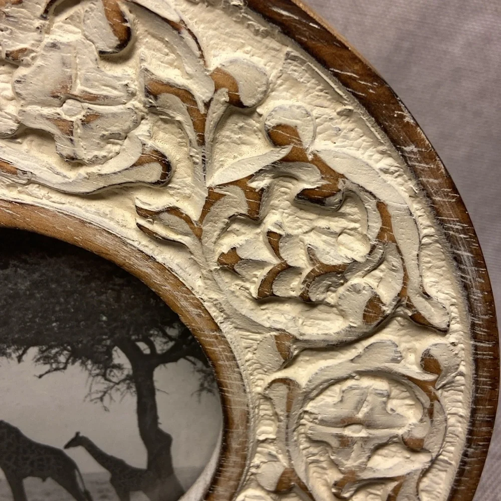 Decorative round, carved wooden picture frame with a distressed white finish.